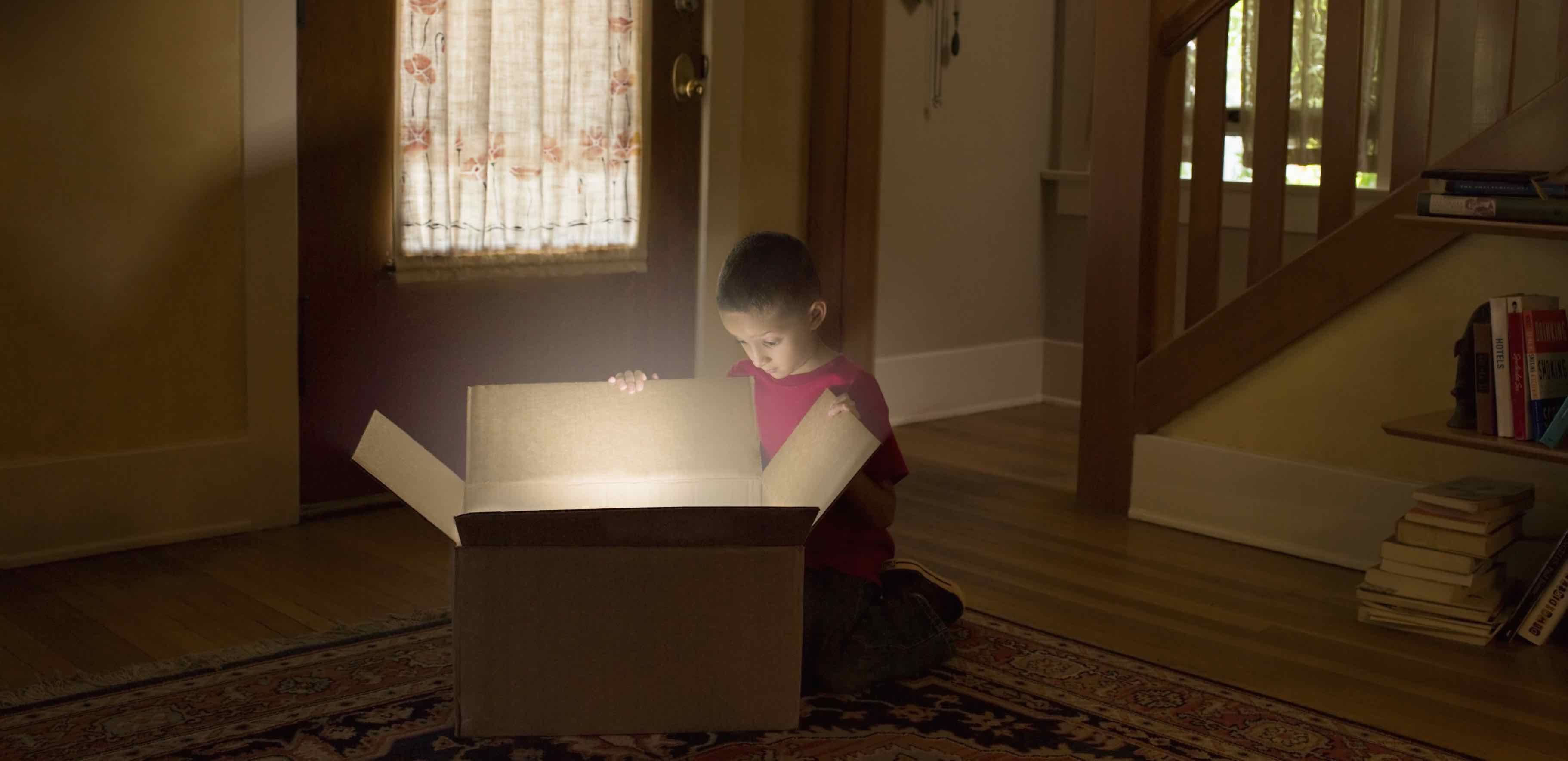 Boy looking into box with light illuminating out